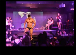 Male stripper on stage taking off his clothes for the crowd.